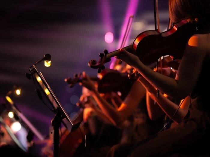 Close up of violin players on stage.